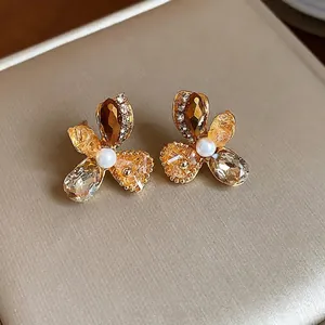 Elegant gold-tone glass flower stud earrings with champagne crystals and center pearl