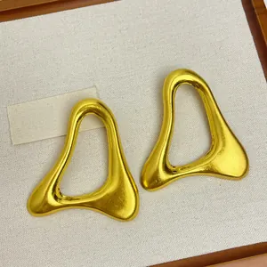 Gros plan de boucles d'oreilles géométriques irrégulières en métal doré sur fond de toile