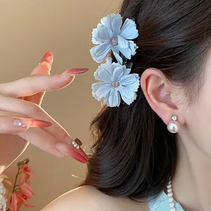Primo piano di eleganti fermagli per capelli a fiore azzurro e orecchino di perla