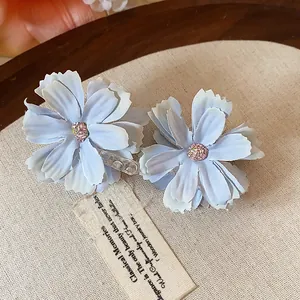 Vista dettagliata di due eleganti fermagli per capelli a fiore azzurro su tessuto