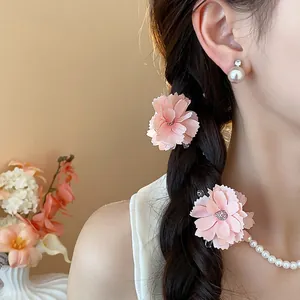 Vista dettagliata di fermagli per capelli a fiori rosa in tessuto su un'acconciatura a treccia