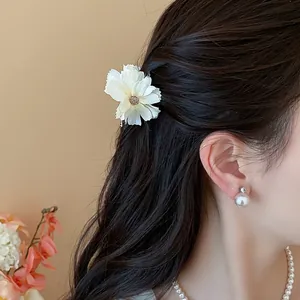 Primo piano di un'elegante pinza per capelli a fiore bianco su capelli mossi scuri