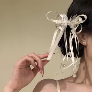 Detailed view of an elegant cream ribbon hair clip with rhinestone butterfly on dark hair