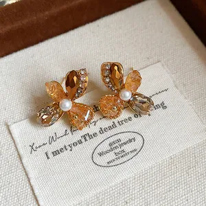 Detailed view of French vintage flower stud earrings with amber crystals and pearl center