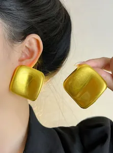 Vue détaillée des boucles d'oreilles carrées dorées surdimensionnées sur le modèle