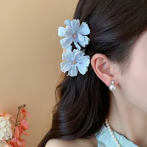 Primo piano di eleganti fermagli per capelli a fiore in tessuto azzurro su una modella