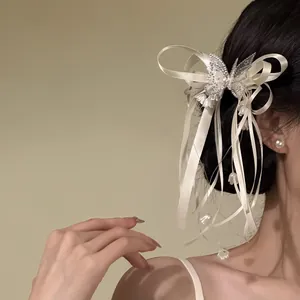 Elegant rhinestone butterfly hair clip with white ribbon bow and long tassels on model