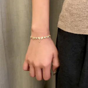 Close-up detail of 18K real gold plated zircon bow and starburst charm on a pull-type bracelet