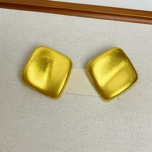 Gros plan de boucles d'oreilles carrées géométriques dorées avec finition satinée mate