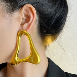 Gros plan de boucles d'oreilles dorées géométriques portées par un mannequin