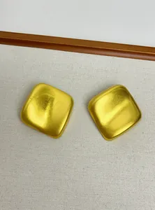 Détail de boucles d'oreilles géométriques dorées avec une texture métallique irrégulière