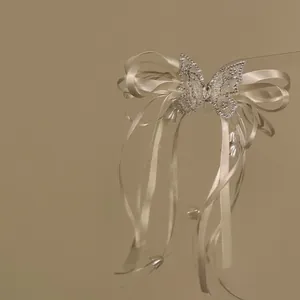 Detail showing elegant satin ribbon bow with sparkling rhinestone butterfly and tassels.