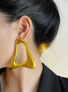 Gros plan d'une grande boucle d'oreille géométrique dorée irrégulière sur un modèle