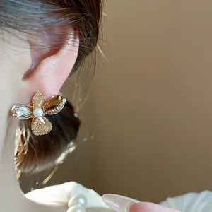 Close-up of elegant flower stud earring with glass crystals and central pearl