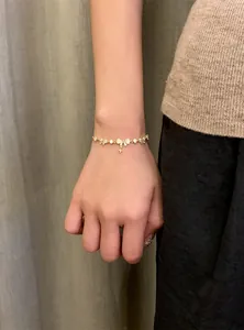 Detailed macro view of 18K gold plated zircon bow and star charm bracelet on female wrist