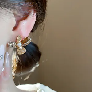 Close-up of elegant flower stud earring with amber glass petals and central pearl.