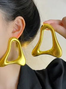 Grandes boucles d'oreilles géométriques dorées sur modèle avec design ajouré unique