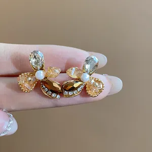 Close-up of elegant flower-shaped earrings with amber crystals and a pearl center.