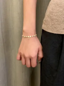 Close-up of 18K gold plated zircon bracelet with bow and star charms on wrist