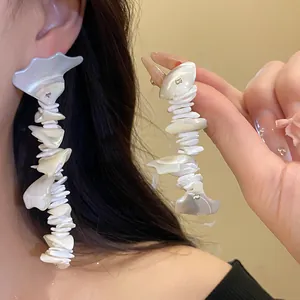 Detailed shot of bohemian long tassel earrings made of irregular white shell fragments.