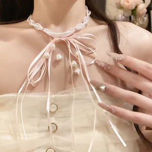 Close-up of sweet pink ribbon bow necklace with white pearl beads and lily flower