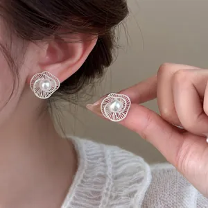 Detailed view of elegant silver hollow spiral earrings with a pearl center on ear