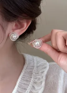 Macro detail of elegant silver hollow spiral stud earrings featuring a center white pearl