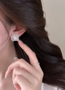Exquisite close-up view of hollow spiral silver stud earring with pearl on female model