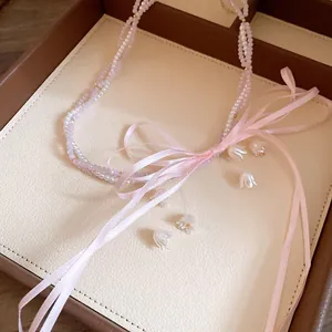 Detailed macro view of a pink beaded necklace with lily-of-the-valley charms and a silk ribbon bow