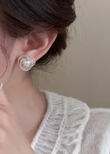 Detailed view of elegant silver hollow spiral pearl stud earring on an Asian model