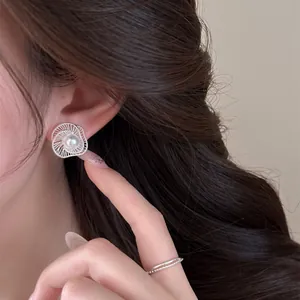 Close-up of elegant hollow-out spiral earrings with pearl worn by model