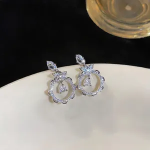 Macro detail of elegant silver-colored floral lace stud earrings with sparkling zircon stones