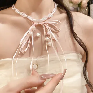 Close-up of pink and white pearl beaded necklace with ribbon bow and lily-of-the-valley tassels