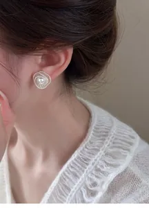 Close-up shot of an elegant hollow swirl pearl stud earring worn on a female model