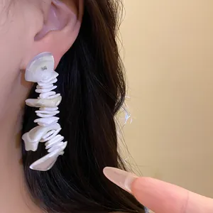 Bohemian style irregular white shell tassel earrings with silver needles on model
