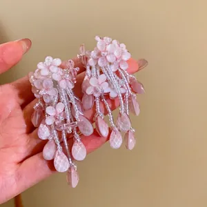 Gros plan sur des boucles d'oreilles à pampilles en fleurs roses et gouttes d'eau.