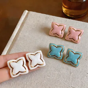 Detail of elegant star flower stud earrings with colorful enamel finish and gold trim.