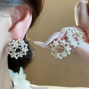Close-up of elegant 14k gold plated pearl wreath earrings with luxury bowknot detail