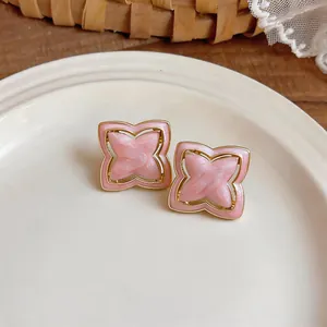 Macro detailed view of elegant pink star-shaped flower stud earrings with gold trim