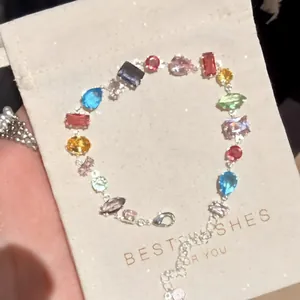 Vista dettagliata di un bracciale in zircone colorato su un sacchetto regalo beige testurizzato
