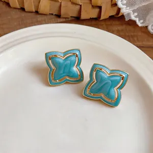 Close-up detail of exquisite turquoise starburst earrings with gold trim on a white plate