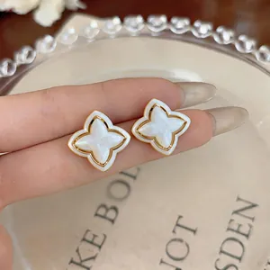 Detailed macro view of white enamel flower stud earrings featuring elegant gold-plated edges