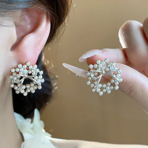 Detailed macro view of elegant 14k gold plated bow and pearl wreath stud earrings