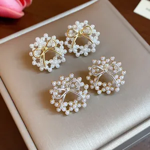 Detail view of pearl bow earrings in gold and silver finishes on a display box