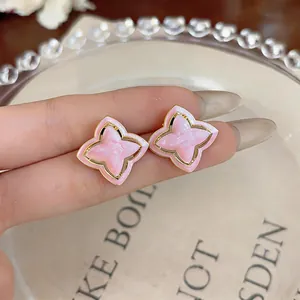 Close-up of elegant pink star flower stud earrings with gold edges and glitter enamel finish