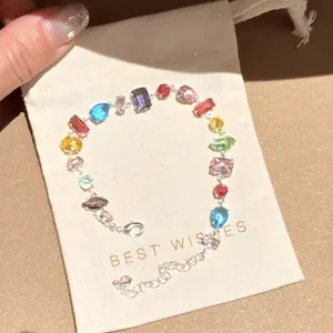 Primo piano di un bracciale in zircone multicolore su un sacchetto regalo crema