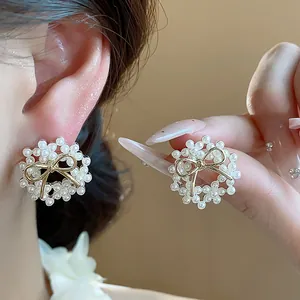 Close-up of elegant bow pearl stud earrings with 14k gold plating on a model