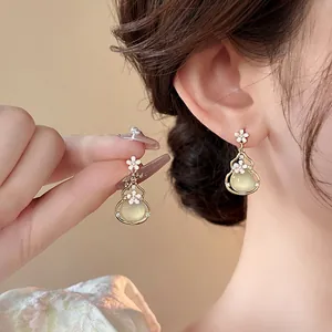 Macro view of elegant palace style gourd drop earrings with floral details and green stone