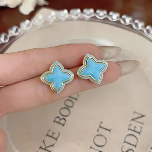 Close-up of light blue enamel starburst flower stud earrings with gold trim