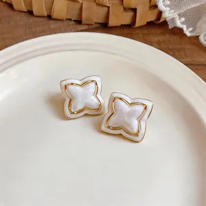 Detailed view of elegant gold-rimmed clover earrings with pearlescent white petals